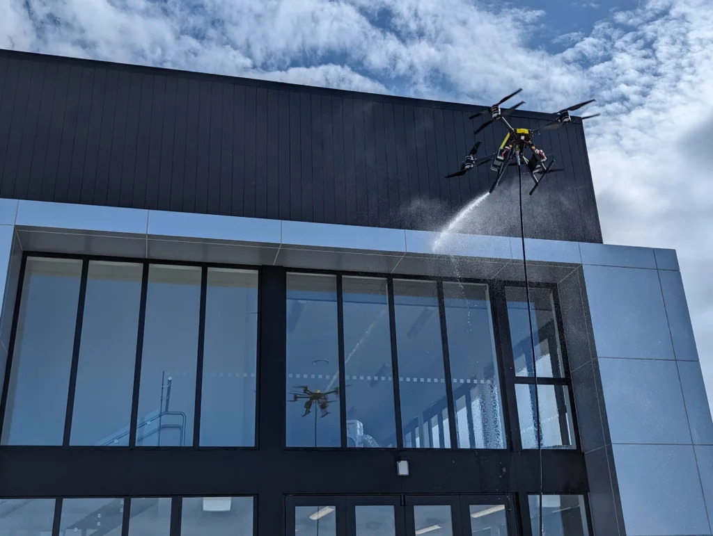 Drone graffiti removal service cleaning a commercial building exterior